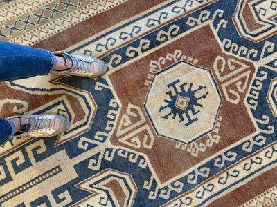 Woman standing on a blue & green extra large Kars Turkish Rug.