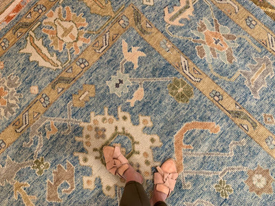 Woman standing on a blue & green Kars Turkish area rug.