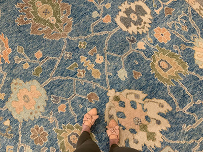 Woman standing on a blue & green Oushak Turkish area rug with tan leather slides.