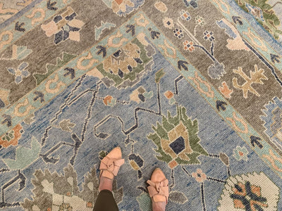 Woman standing on a blue & green area rug Oushak Turkish Rug.