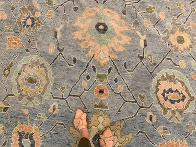 Woman standing on a blue & green area rug Oushak Turkish Rug.