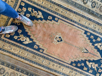 Woman standing on a blue & green medium Sivas Turkish Rug.