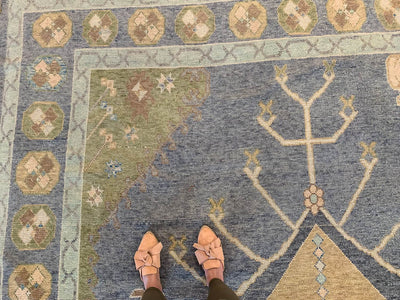Woman standing on a blue & green Oushak Turkish area rug.