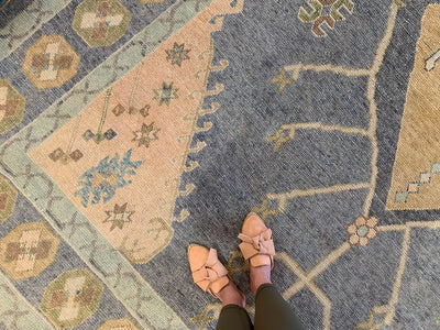 Woman in leather flats standing on a blue & green Oushak Turkish area rug.