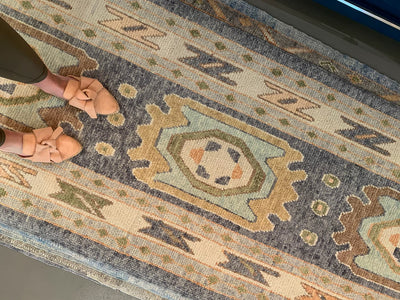 Woman standing on a blue & green Turkish runner rug.