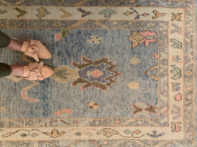 Woman standing on a blue & green Turkish runner rug.