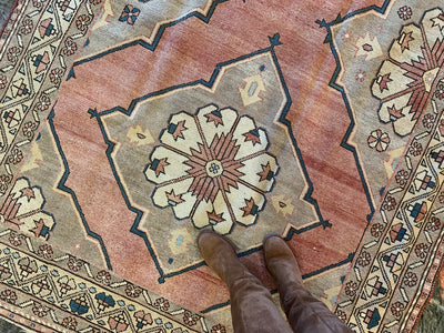 Woman in riding boots standing on a large red & orange Konya Turkish rug.