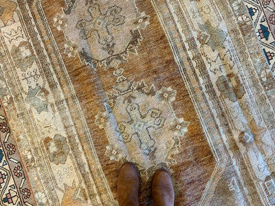 Woman standing on a medium red & orange Bor Turkish rug.