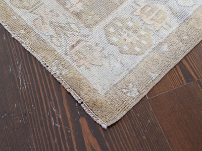 Close up of the corner of a brown & grey medium sized Maden Turkish rug.