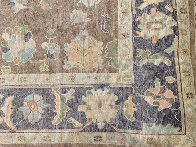 Corner of a brown & grey Oushak Turkish area rug.