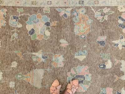Woman standing on a brown & grey Oushak Turkish area rug.