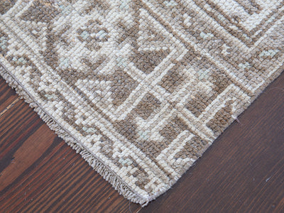 Corner of brown & grey Oushak Turkish rug runner.