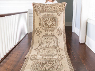 Woman holding brown & grey Oushak Turkish rug runner.