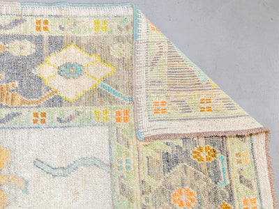 Corner of extra large brown & grey Turkish Oushak rug turned over.