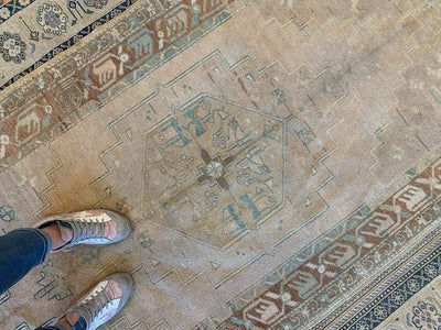 Central medallion of a medium brown and grey Sivas Turkish rug with woman's feet.