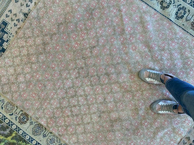 Top down of medium brown and grey Sivas Turkish rug with womans feet.