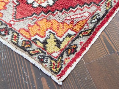 Corner of a red & orange extra small Turkish Yastik Rug showing piling.