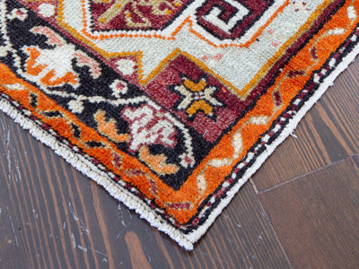Corner of a red & orange extra small Turkish Yastik Rug,