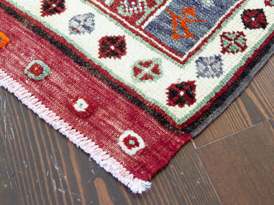 Corner of a red & orange extra small Turkish Yastik Rug.