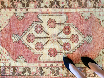 Woman standing on a small red & orange Cal Turkish rug.