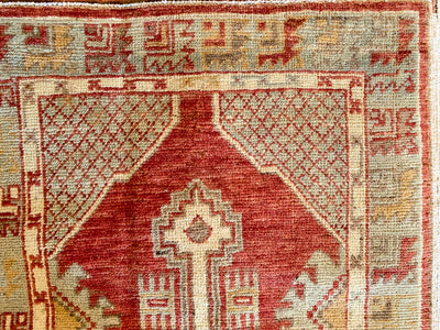 Close up of hand knotting on a small red & orange Cal Turkish rug.