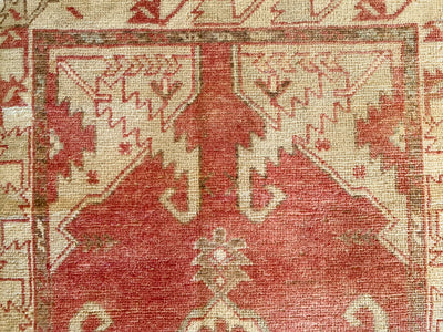 Close up of hand knotting on a small red & orange Cal Turkish rug.