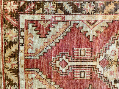 Close up of corner and hand knotting on a small red & orange Cal Turkish rug.