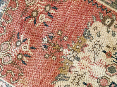 Close up on a hand knotted small red & orange Guney Turkish rug.