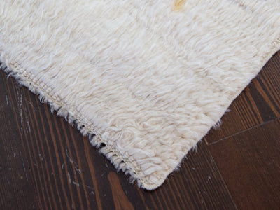 Corner of a white medium Turkish Tulu rug.