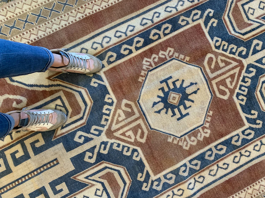 Woman standing on a blue & green extra large Kars Turkish Rug.