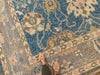 Woman in tan slides on the corner of a blue & green Oushak Turkish area rug.