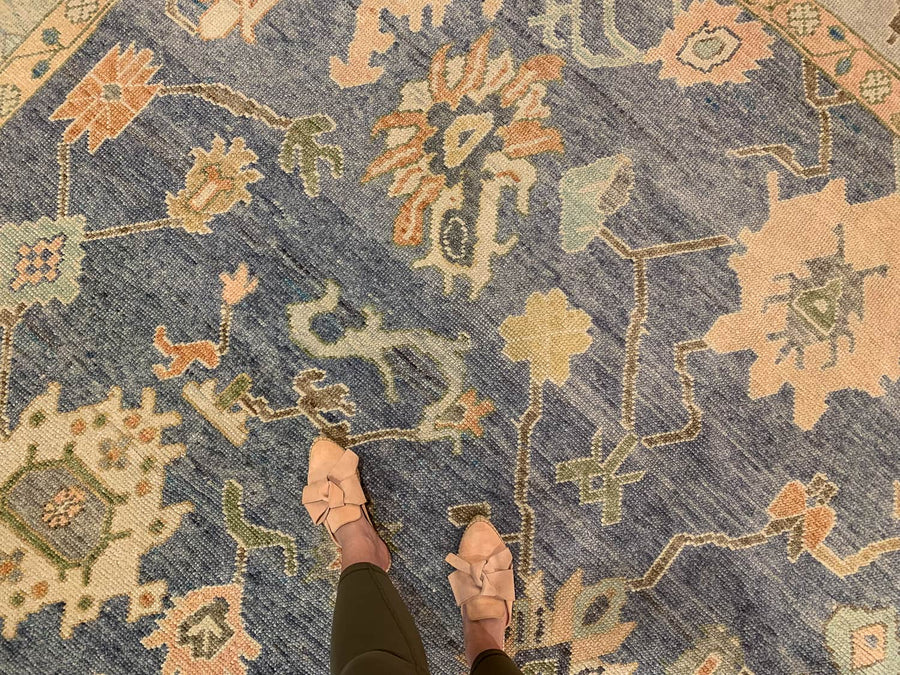 Woman standing on a blue & green Oushak Turkish area rug.