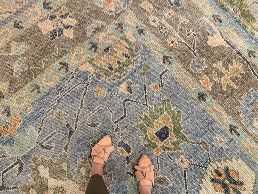 Woman standing on a blue & green area rug Oushak Turkish Rug.
