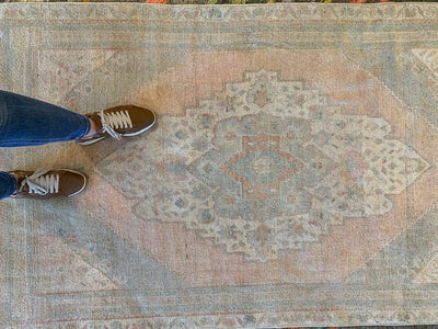 Medium blue/green Sivas Turkish Rug with womans feet in brown shoes.