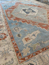 Full rug shot of Red and orange Oushak Turkish area rug.