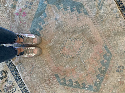Woman in trendy shoes standing on a blue & green medium Bor Turkish Rug