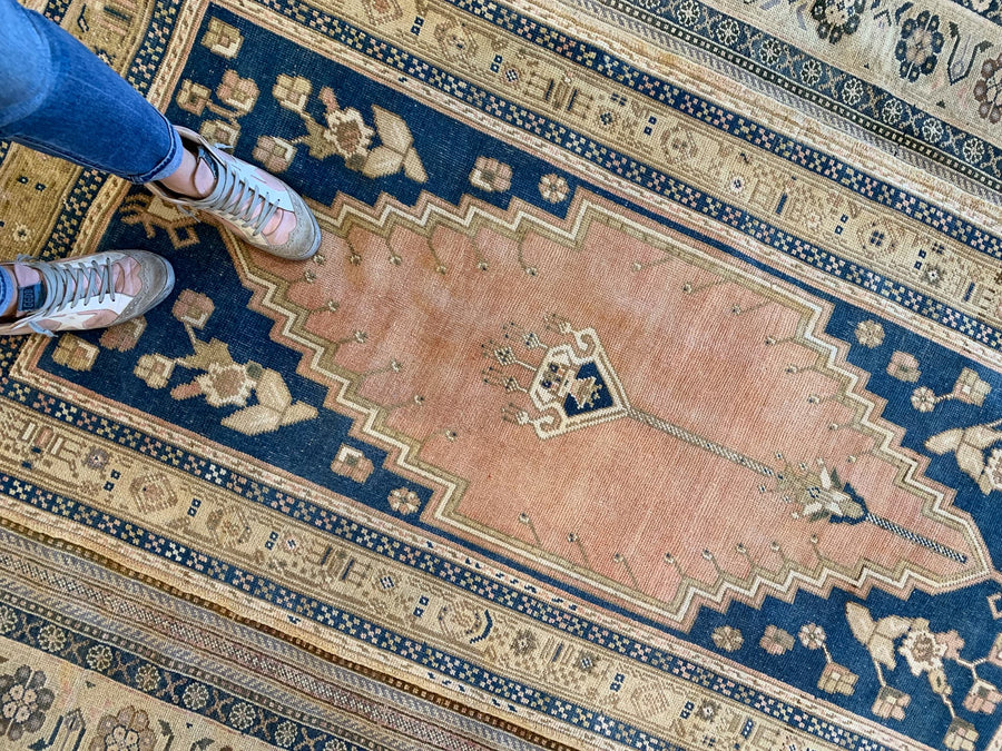 Woman standing on a blue & green medium Sivas Turkish Rug.
