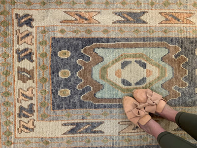 Woman in leather flats on a blue & green Turkish runner rug.