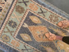 Woman in tan leather flats standing on a blue & green Turkish runner rug.