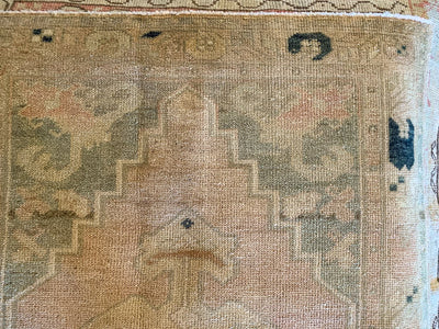 Close up of faded patterns on a vintage small blue & green For Turkish rug.