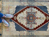 Woman standing on a blue & green small Sivas Turkish Rug.
