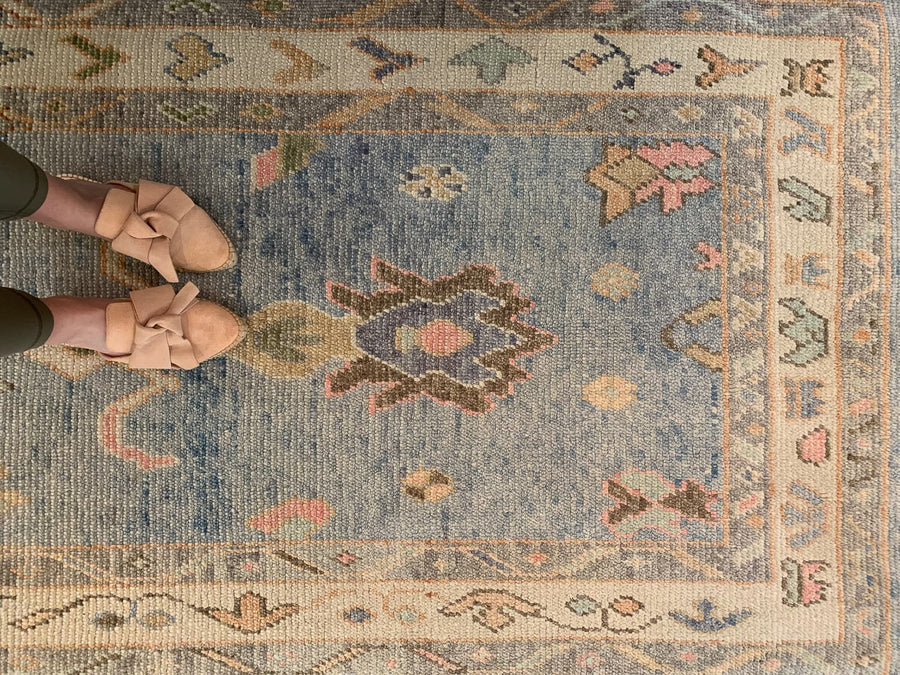Woman standing on a blue & green Turkish runner rug.