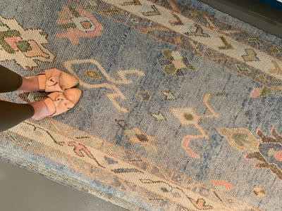 woman standing on a vintage blue & green Turkish runner rug.