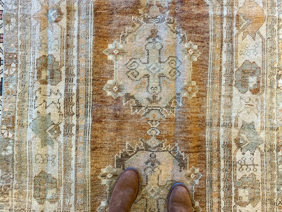 Woman standing on a medium red & orange Bor Turkish rug.