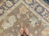 Woman in tan leather flats standing on a brown & grey Oushak Turkish area rug.