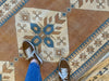 Woman standing on a brown & grey Sultahan runner Turkish rug.