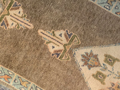 Close up of knot work and medallion on a brown & grey Turkish runner rug.