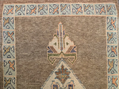 End knot work on a brown & grey Turkish runner rug.