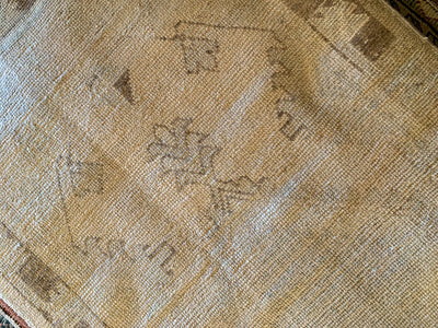 Close up of faded medallion and motifs on a vintage small brown & grey Cal Turkish rug.