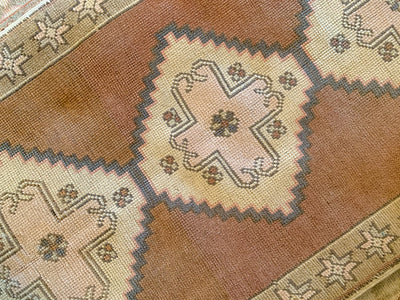 Close up of central medallion on a small brown & grey Sultanhan Turkish rug.